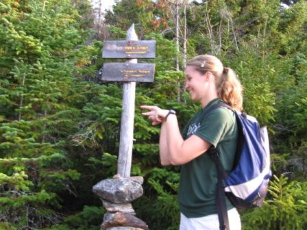 Woman pointing near a sign.